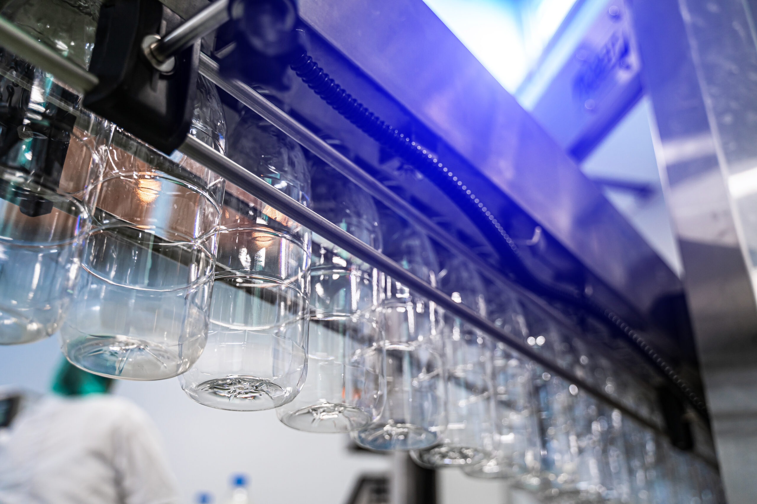 Clear bottles transfer on conveyor belt system. Transparent bottles. Dairy or juice production.