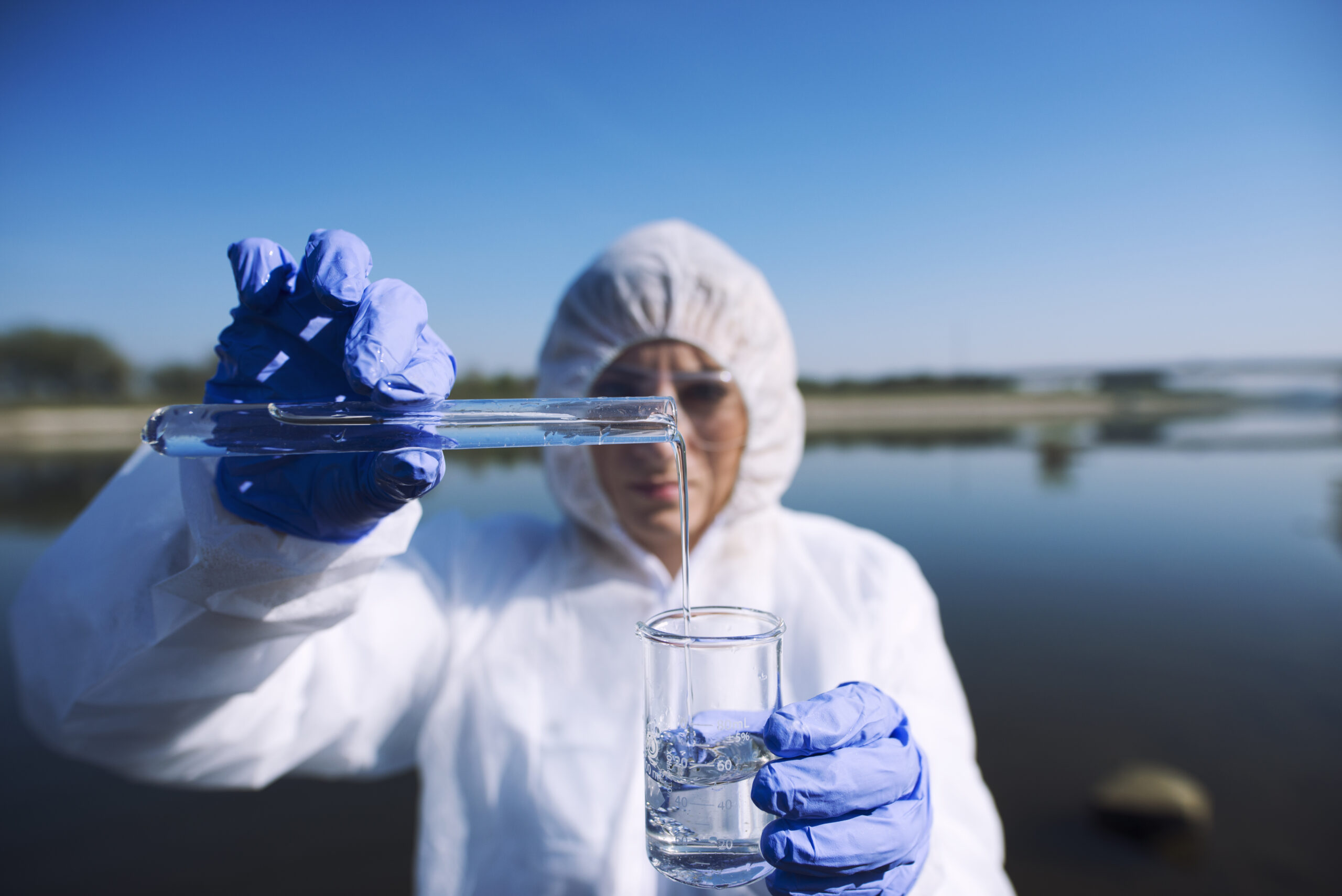Ecologist sampling water from the river with test tube.